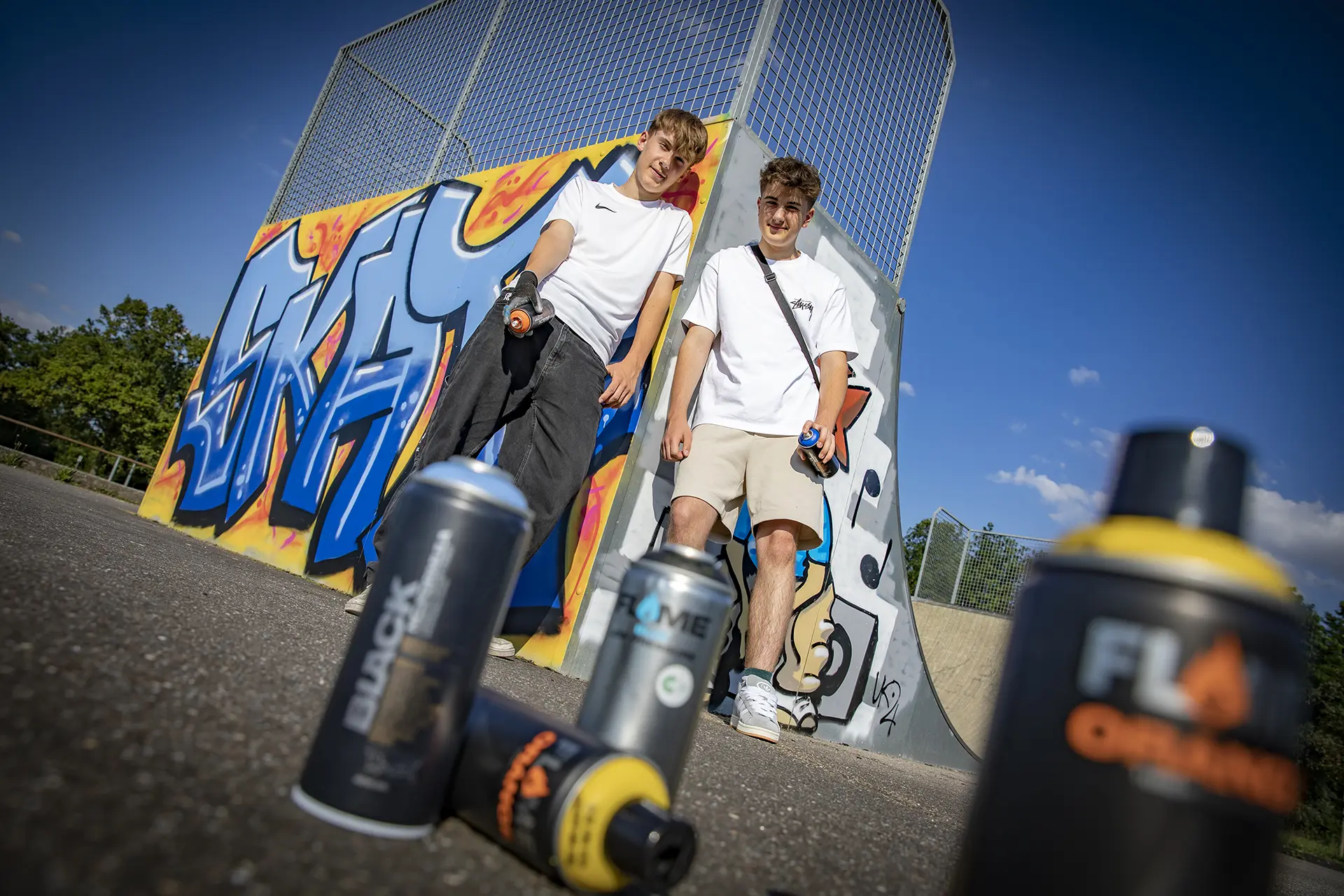 Zwei Jugendliche stehen mit Ihren Spraydosen vor einer Halfpipe